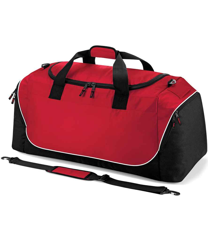 The Quadra Teamwear Jumbo Kit Bag by Quadra in red/black features a large zippered main compartment, black handles, side pockets, and an adjustable shoulder strap positioned at the front.