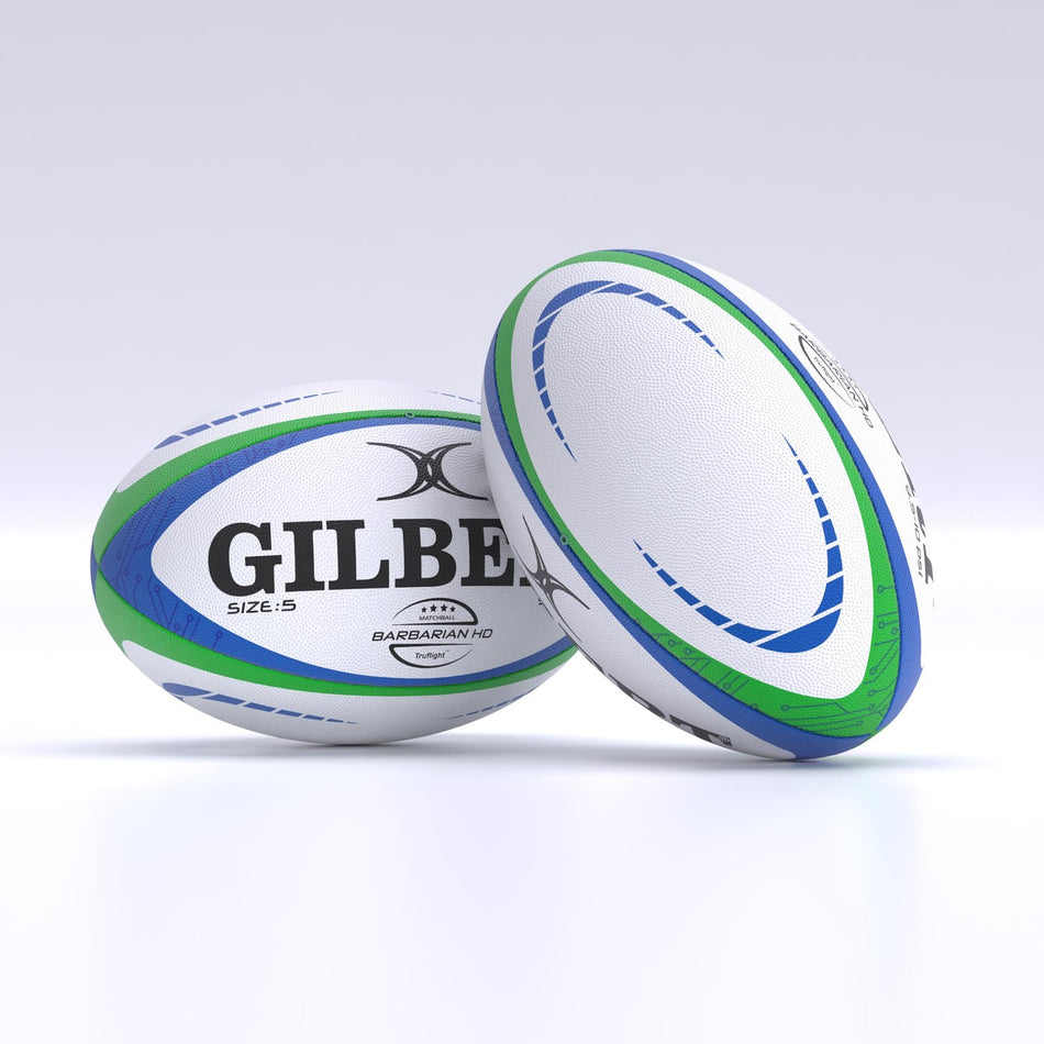 Two white Gilbert Barbarian HD Match Rugby Balls are on a smooth surface. One lies flat with the Gilbert logo visible, while the other stands upright, showing its side and blue-green patterns.