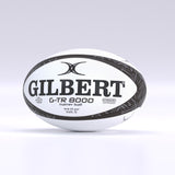 A black Gilbert G-TR8000 Training Rugby Ball by Gilbert, featuring durable rubber construction with HYDRATEC and size details printed on it, is displayed on a light background.