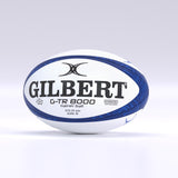 A navy Gilbert G-TR8000 Training Rugby Ball by Gilbert is displayed on a plain light background, featuring large black branding and text that identifies it as a size 5 ball crafted from durable rubber.