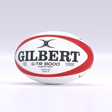 A red Gilbert G-TR8000 Training Rugby Ball is displayed on a plain, light-gray background. The durable rubber ball features black and red branding, as well as size and pressure details printed on its surface.