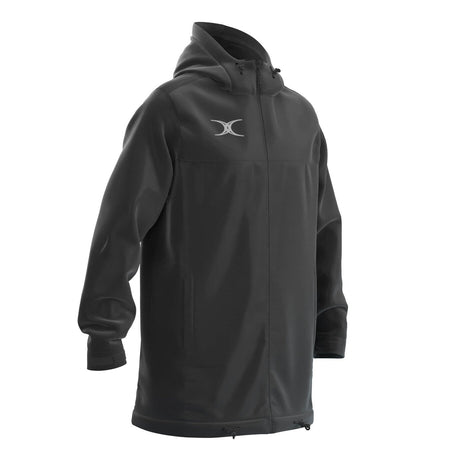 The Gilbert TTS All Weather Jacket by Gilbert is a long, black waterproof jacket made from recycled polyester with a front zipper, drawstring hood and hem, white chest logo, long sleeves, and a relaxed fit.