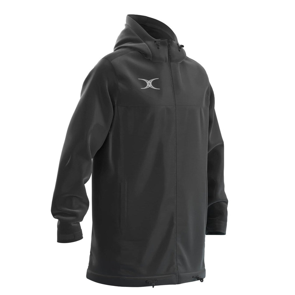 The Gilbert TTS All Weather Jacket by Gilbert is a long, black waterproof jacket made from recycled polyester with a front zipper, drawstring hood and hem, white chest logo, long sleeves, and a relaxed fit.