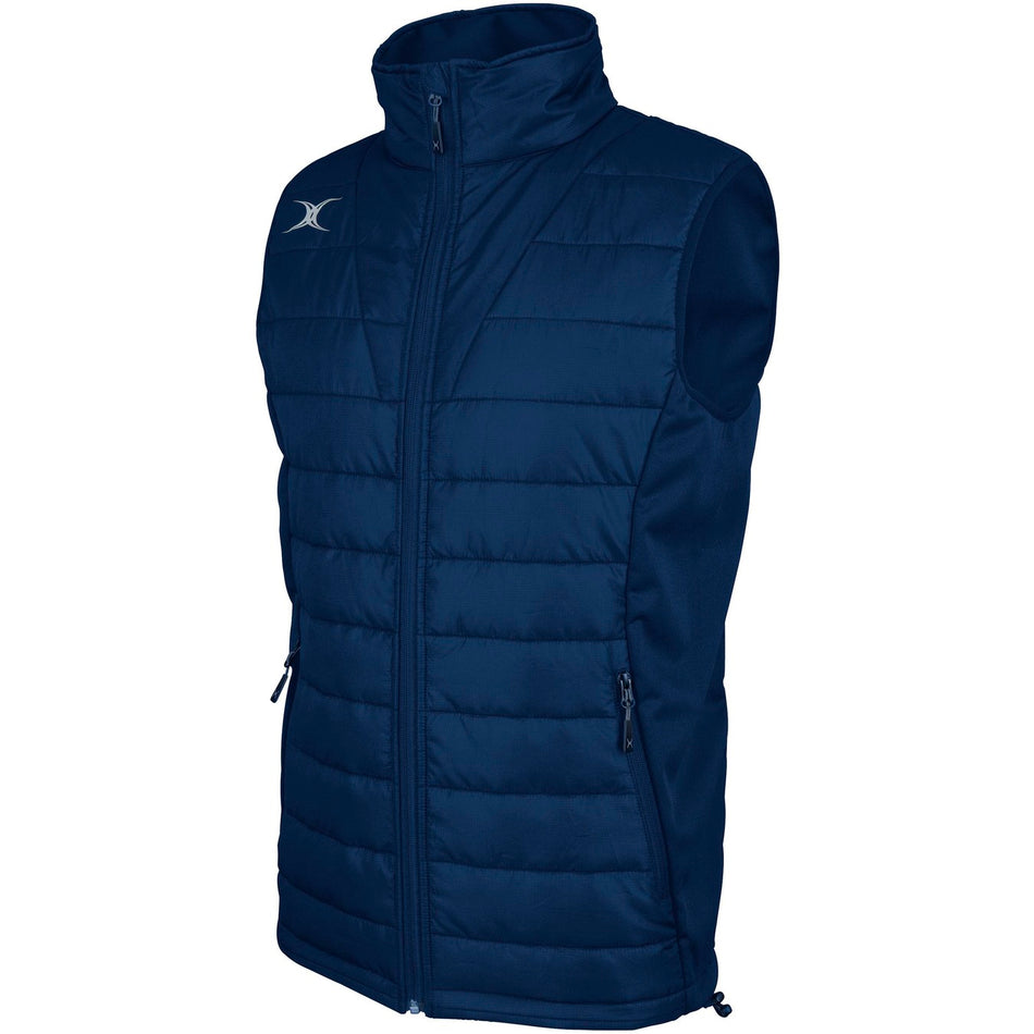 The Gilbert Pro Body Warmer by Gilbert is a sleeveless, navy quilted vest with a high collar, front zipper, two zippered pockets, and a small white logo on the upper left chest. Made from breathable technical fabric.