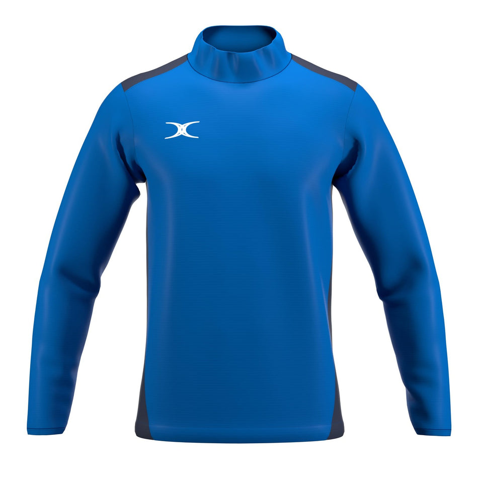 The Gilbert Atom Warm Up Jacket is a blue, long-sleeve athletic jacket with dark side panels, a high collar, and a white Gilbert logo on the left chest. It’s shown on a plain white background.