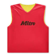 The Mitre Reversible Training Bib features a red exterior and yellow interior, with the Mitre brand name printed in black on the front.