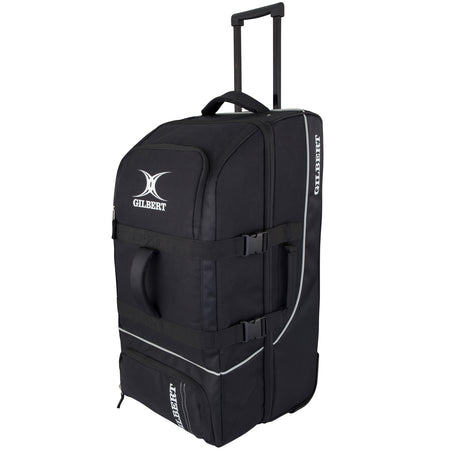 The Gilbert Club Tour Wheeled Holdall, a large black sports travel bag by Gilbert, features wheels, a telescopic handle, side straps, and a zippered front pocket. It is shown standing upright on a white background.