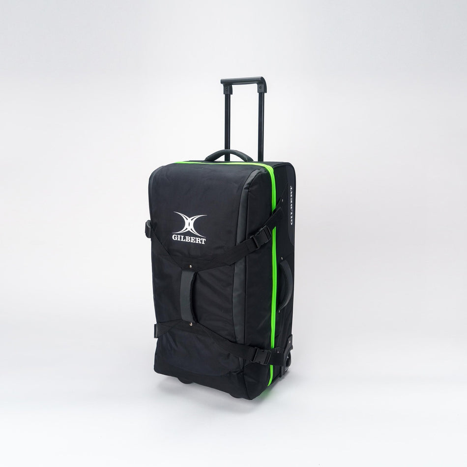 The Gilbert Club Tour Bag V4 by Gilbert is a large black wheeled holdall with a retractable handle, green trim, and the Gilbert logo on the front, shown standing upright on a white background.
