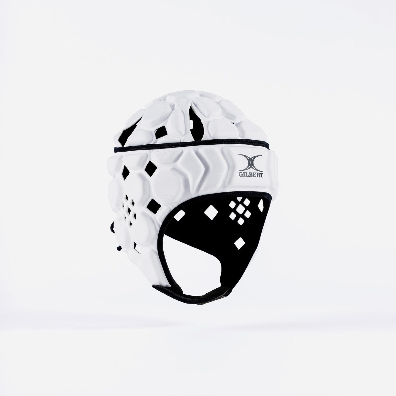 The Gilbert Octane Junior Headguard in White/Black, featuring diamond-shaped cutouts, a front Gilbert logo, and an expandable lace closure, is shown against a plain white background.