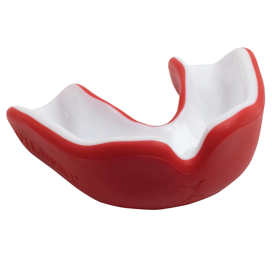 The Gilbert Virtuo Dual Density Mouthguard, in red/white, provides advanced concussion protection. The front view highlights its sturdy red outer layer and white inner section for sports safety.