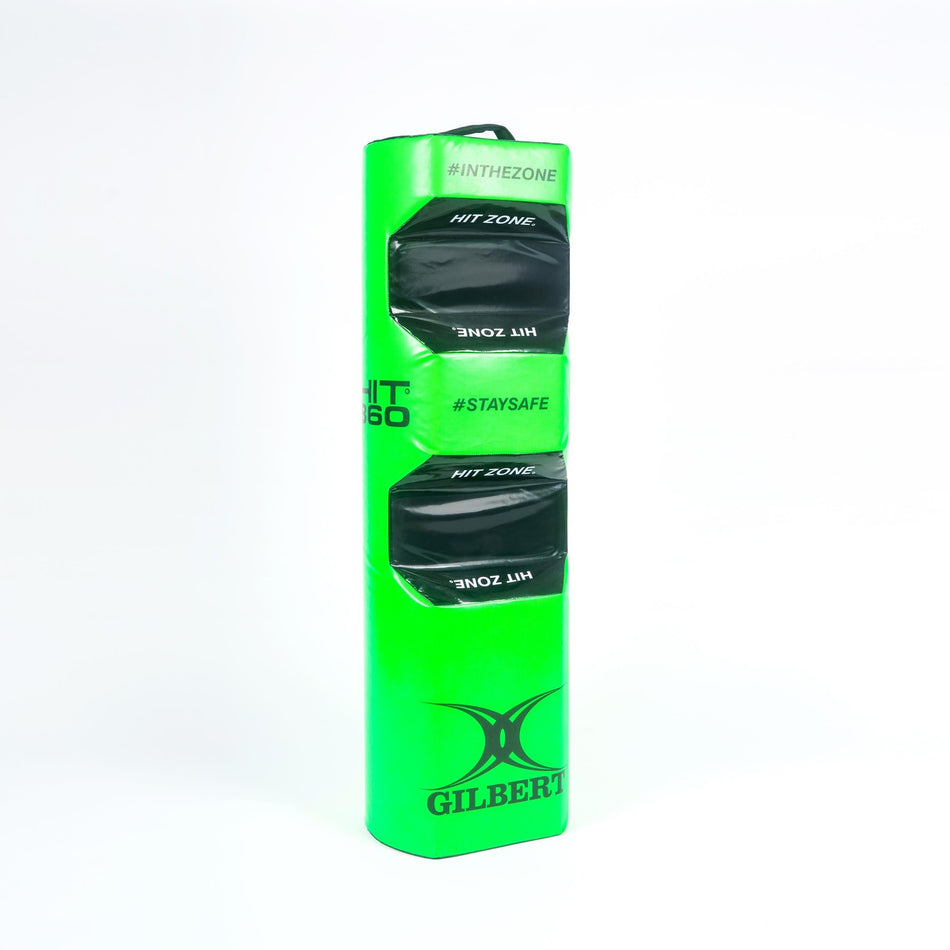 The Gilbert Hit 360 Tackle Bag is a tall, rectangular green bag with black HIT ZONE sections and Gilbert branding, designed for rugby tackle training and safety by clearly marking the correct legal tackle height.
