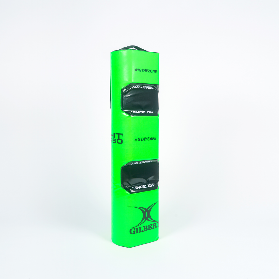 The Gilbert Hit 360 Tackle Bag is a bright green rectangular rugby tackle bag with two black handles and branded #INTHEZONE and #STAYSAFE—ideal for legal tackle training at the right height, shown upright on a white background.
