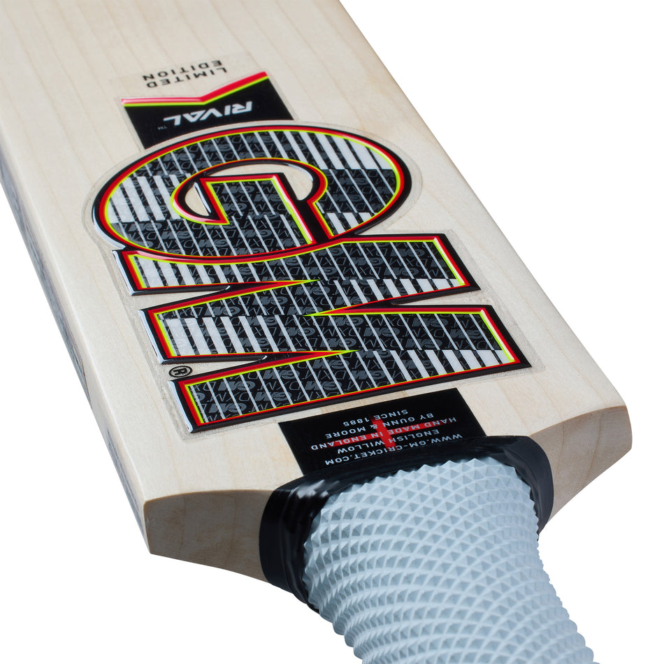 Close-up of a Gunn & Moore Rival DXM Junior Cricket Bat 2026 showing its flat English willow blade marked with "10" and "Rival," plus a light gray Apex grip handle, designed by Gunn & Moore for better control with a low swell profile.
