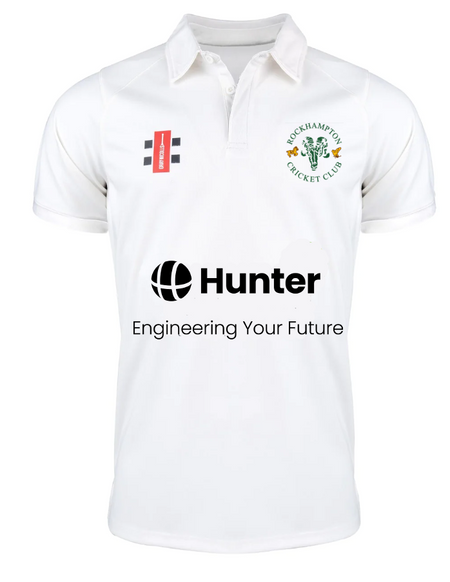 The Gray Nicolls Rockhampton CC Pro Performance Short Sleeved Shirt - Junior is white with the Rockhampton CC logo on the left chest, two rectangular logos on the right, and "Hunter Engineering Your Future" printed across the front in black.