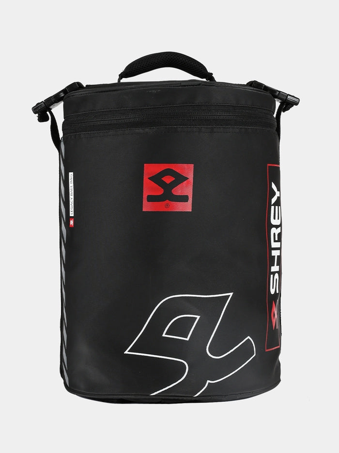 The Shrey Legacy Ball Bag is a black cricket bag with a zipper, top handle, and shoulder strap. Ideal for training equipment, it features white and red Shrey logos and branding on the front and side.
