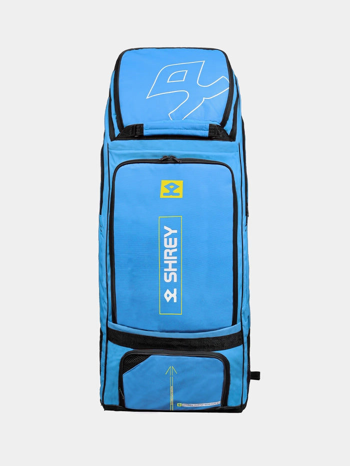 The Shrey Legacy Duffle Wheelie 80, a large Brittany Blue cricket bag with black zippers, yellow accents, and multiple compartments, stands upright against a plain background. The Shrey brand and logo are visible on the 80L bag’s front.
