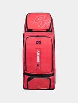 The Shrey Legacy Duffle Wheelie 80, in Radiant Red, is an 80L duffle bag with black trim, multiple zippered compartments, and the Shrey logo on the front. It stands upright against a plain light background.