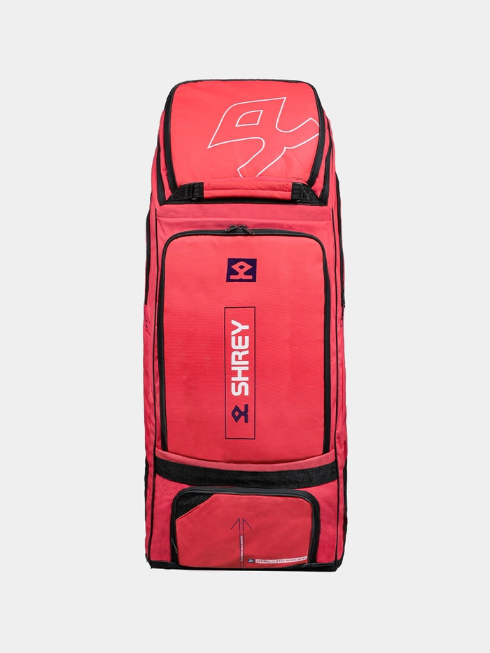 The Shrey Legacy Duffle Wheelie 80, in Radiant Red, is an 80L duffle bag with black trim, multiple zippered compartments, and the Shrey logo on the front. It stands upright against a plain light background.