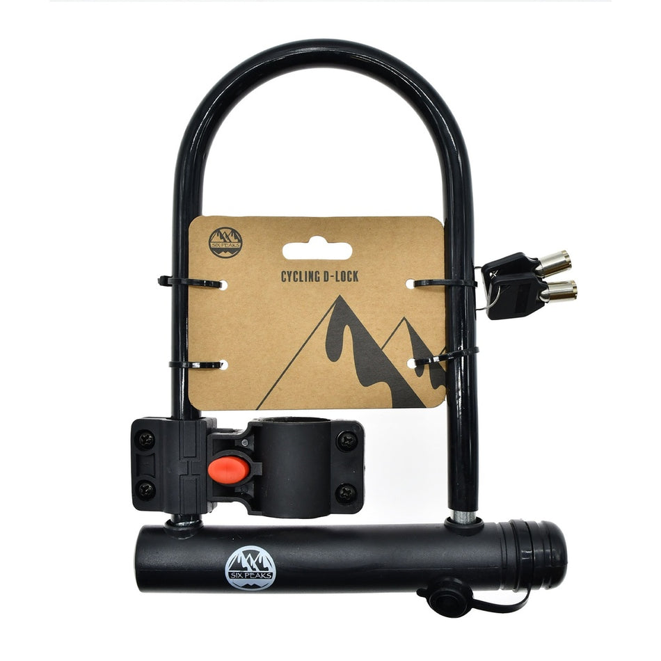 The Six Peaks Cycling D-Lock by Six Peaks is a sturdy black bicycle lock with keys, a mounting bracket, and “Cycling D-Lock” cardboard packaging featuring a mountain graphic, all shown against a white background.