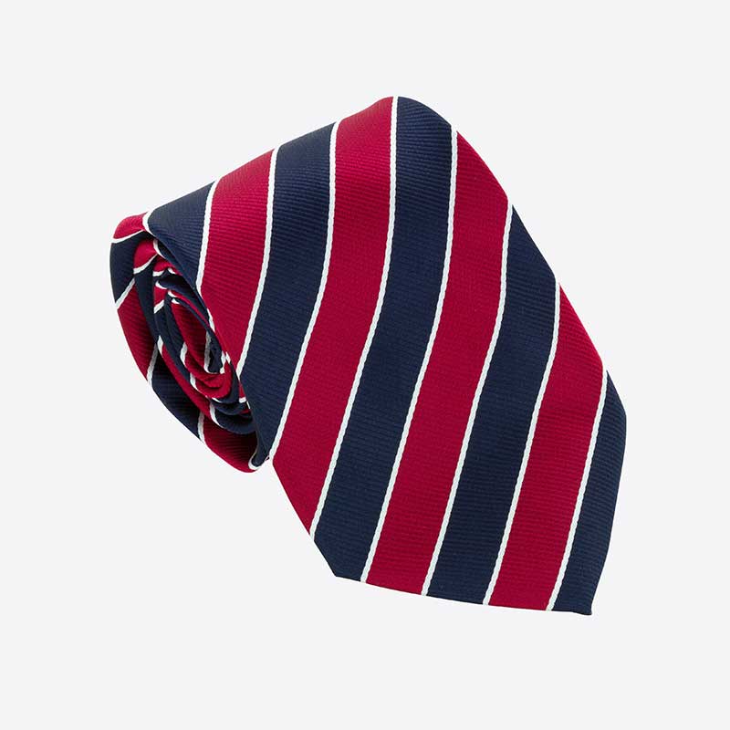 A Custom Club & School Tie by Martin Berrill Sports, featuring diagonal red and navy blue stripes with thin white lines, is rolled up and displayed against a simple light background.
