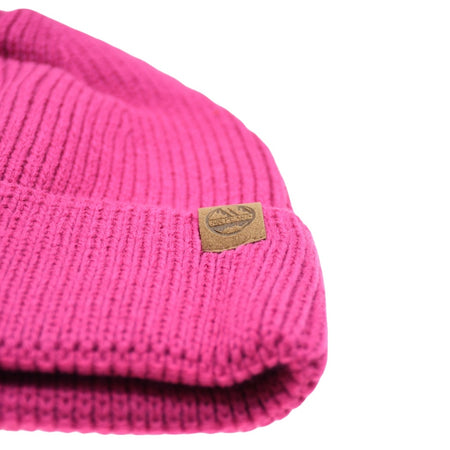A close-up of the bright pink Six Peaks Beanie by Six Peaks, a cozy knit hat with a small brown rectangular logo patch, shown on a white background.