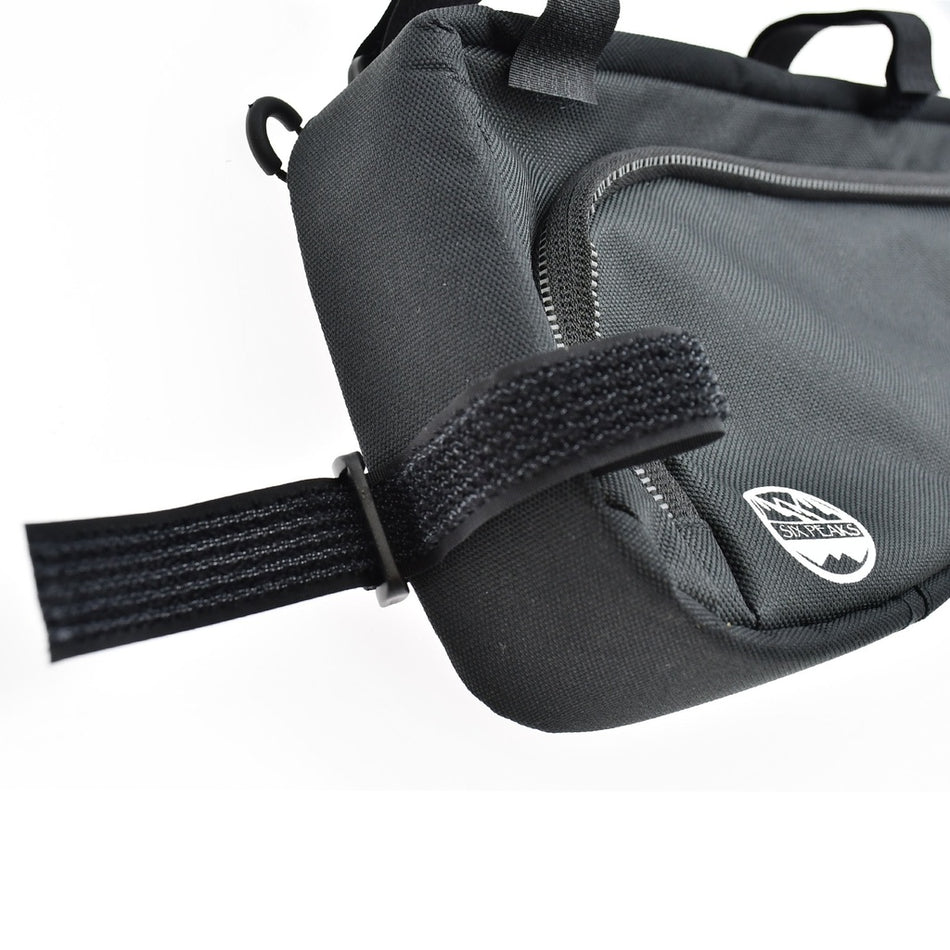 Close-up of the Six Peaks Cycling Triangle Frame Bag in black, featuring a zippered pocket, Velcro strap, and a small shield-shaped logo patch—the ideal bike storage bag for organizing your cycling gear.