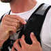 A close-up shows a person adjusting the zipper on the front of a Six Peaks Hydration Running Vest in black with gray details, worn over a white shirt. Only their hands, torso, and lower face are visible.