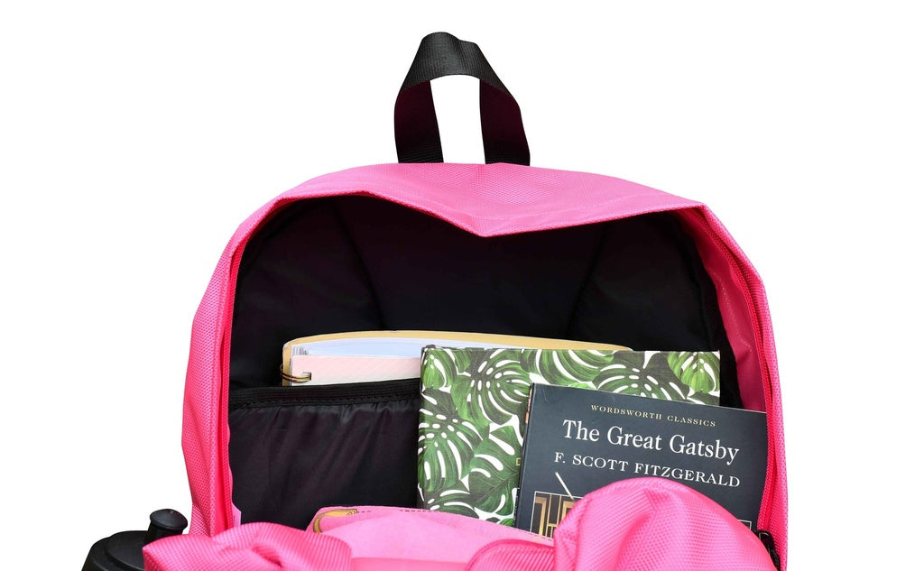 The Six Peaks Icon 30 Liter Backpack in pink is unzipped to show its dedicated laptop sleeve and books inside, including The Great Gatsby by F. Scott Fitzgerald and another book with a green leafy cover.