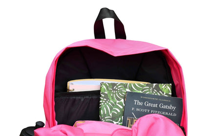 The Six Peaks Icon 30 Liter Backpack in pink is unzipped to show its dedicated laptop sleeve and books inside, including The Great Gatsby by F. Scott Fitzgerald and another book with a green leafy cover.