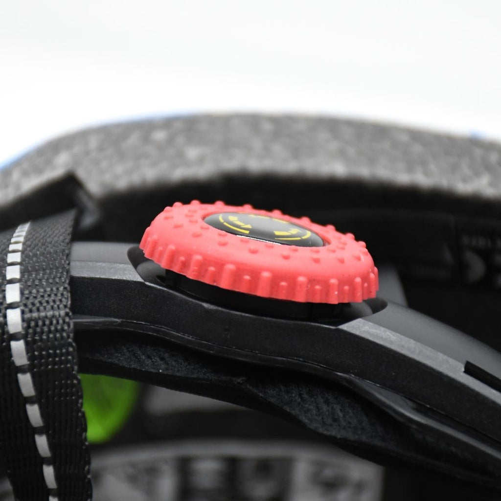 Close-up of a red adjustment dial with a black and yellow center inside the Six Peaks Junior Cycling Helmet by Six Peaks, shown next to a black strap with white stitching and gray foam padding.