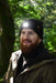 A bearded man wearing the Six Peaks LED Lighted Beanie Hat and a brown jacket smiles outdoors in a sunlit green forest.