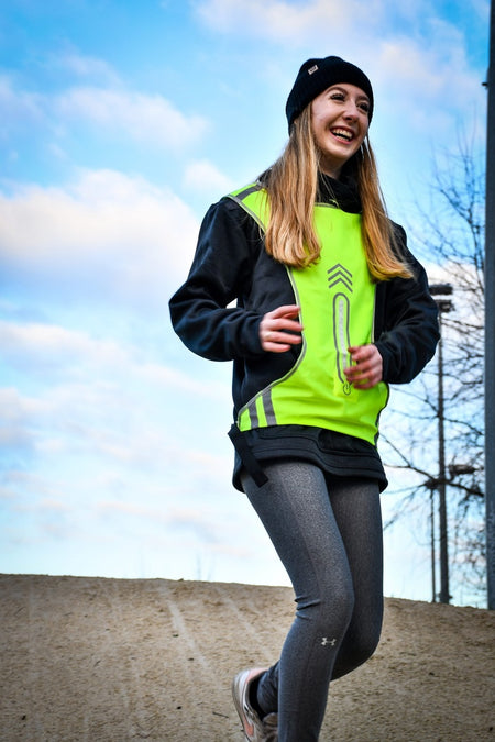 A woman wears a hat and the Six Peaks LED Reflective Sport Vest by Six Peaks.