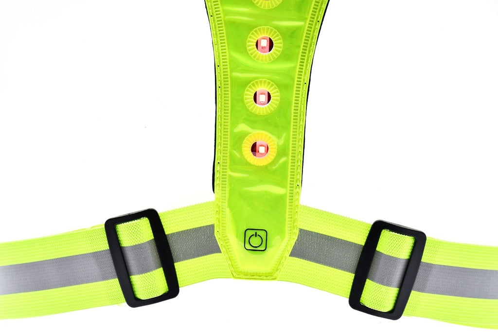 A close-up of the Six Peaks LED Reflective Vest with Phone Holder, featuring neon yellow fabric, red LED lights, an on/off button, adjustable black buckles, and a gray reflective stripe for visibility.