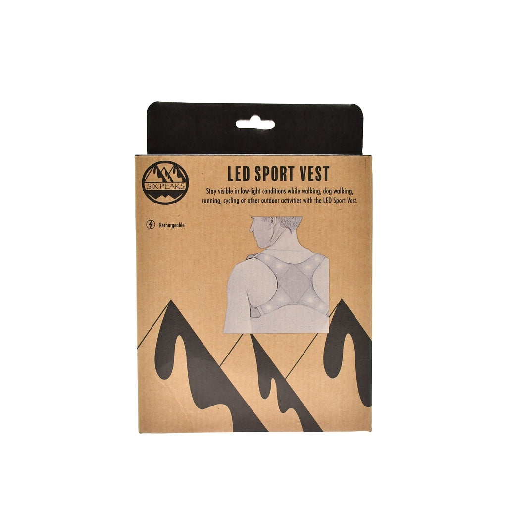 A cardboard box labeled Six Peaks LED Sport Vest features a sketch of a person in this rechargeable safety vest with black mountain silhouettes below and text highlighting visibility for outdoor activities. Brand: Six Peaks.