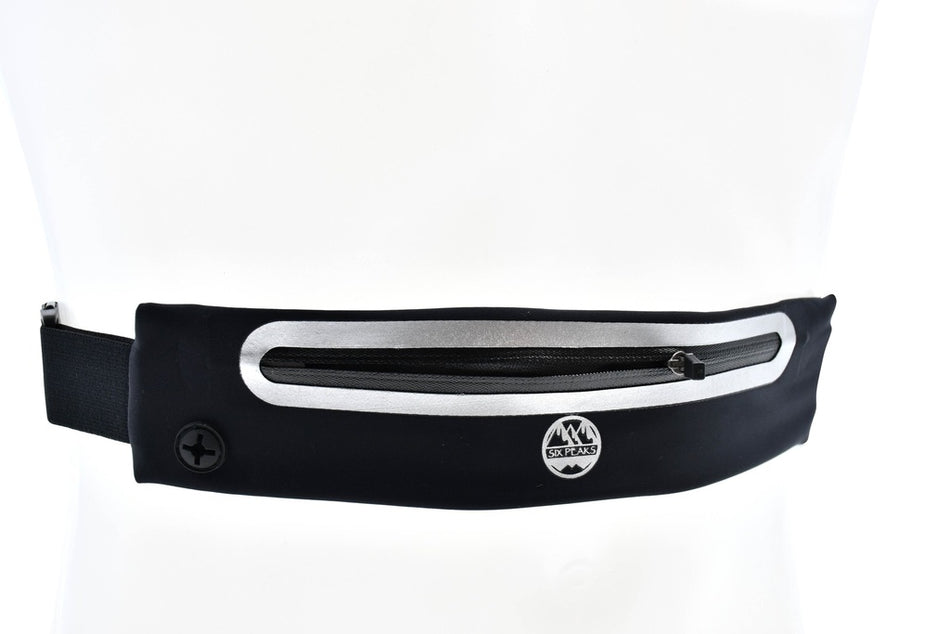The Six Peaks Reflective Running Expandable Waist Belt, in black and silver, features an adjustable elastic strap, zippered pocket, expandable waistband, and a small round front logo. Shown on a white background.