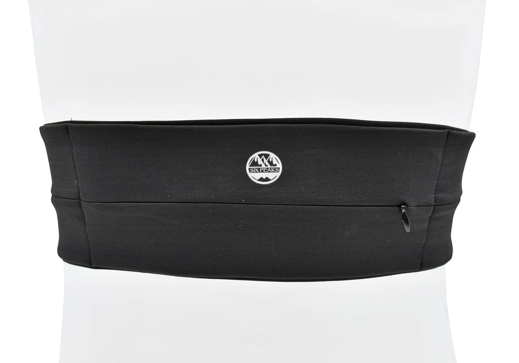 The Six Peaks Running Slim Lightweight Waistband is a black fabric running belt with a zippered pocket and a circular mountain logo, making it the perfect workout accessory. Displayed on a white background.