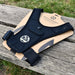 The Six Peaks Running Vest with Phone Holder by Six Peaks, in black with adjustable straps and a zippered phone pocket, is shown on cardboard packaging atop a wooden bench outdoors, with grass visible in the background.