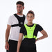 A man and woman wear Six Peaks Running Vests with Phone Holders—a black vest over a white T-shirt for him, a neon green reflective vest over black for her—both from Six Peaks, standing against a plain white background.