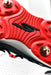 Close-up of the red sole of the Skechers Cricket Elite Cricket Shoe by Skechers, showing textured grooves, gold studs, a central black logo, and Arch Fit insole. The partially visible upper is white with black and red accents.