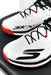 A pair of white Skechers Cricket Elite Cricket Shoes with black laces, red accents, and an Arch Fit insole rest on a black surface.