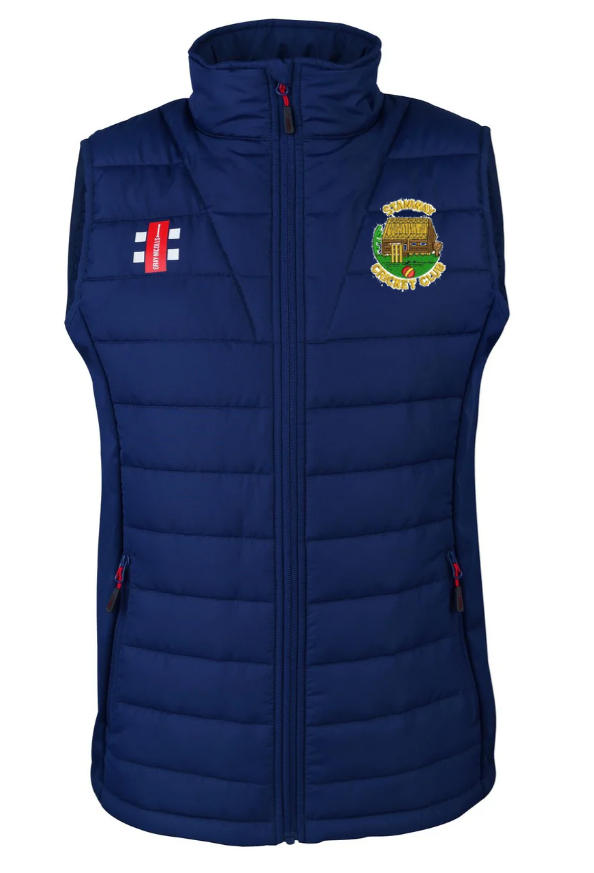 The Gray Nicolls Stanway CC Pro Performance Bodywarmer is a navy blue, padded, recycled polyester vest featuring a high collar, front zip, two zip pockets, an embroidered left chest crest, and a right chest flag emblem.