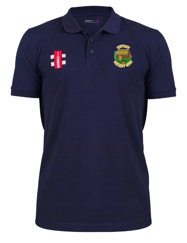 The Gray Nicolls Stanway CC Velocity Polo Shirt in navy blue features organic cotton, a cricket club logo on the left chest, red and white emblem on the right, classic collar, and short sleeves. Displayed on a plain white background.