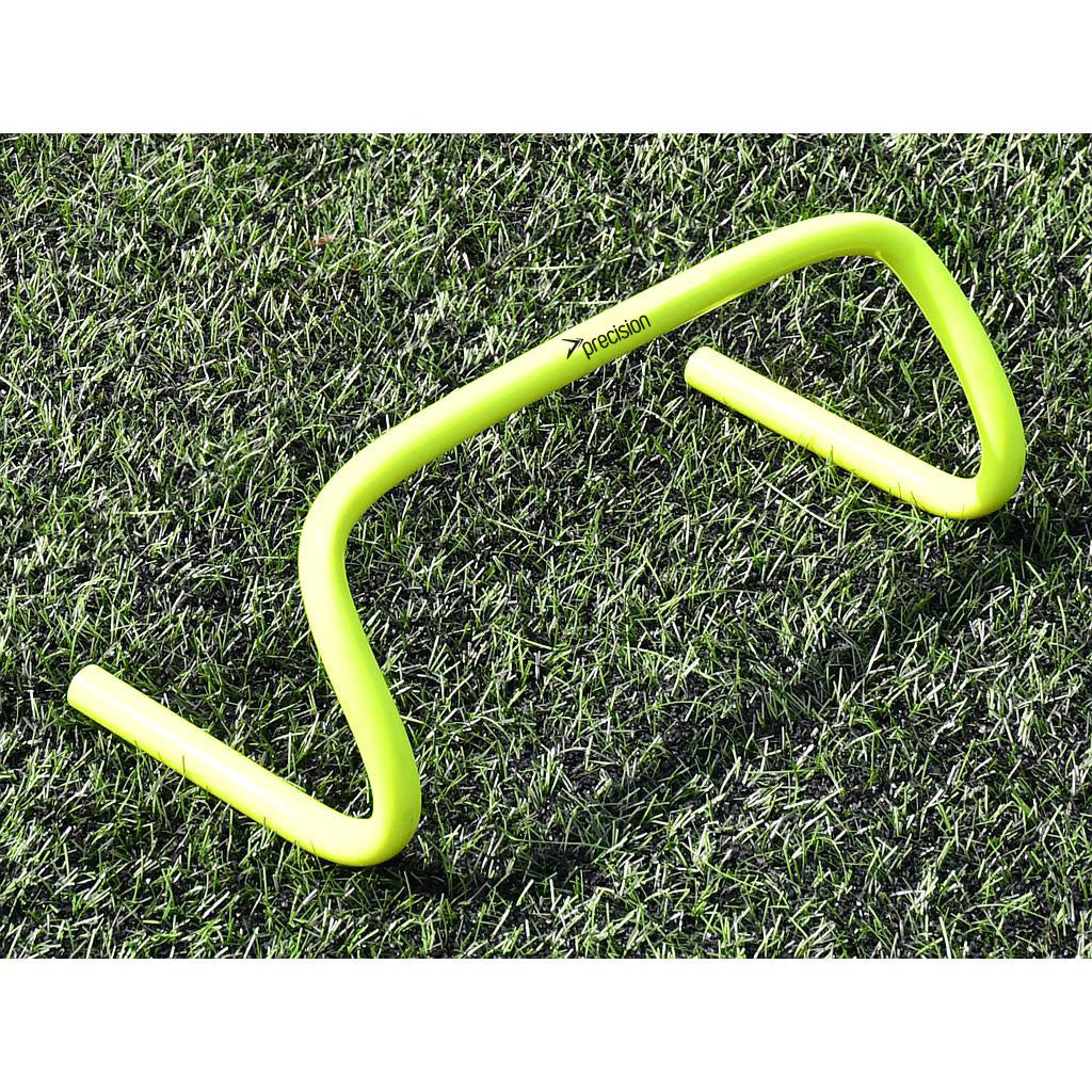 A Precision Training Agility Hurdle in yellow sits on green grass, perfect for lateral speed drills or stride exercises to enhance agility.
