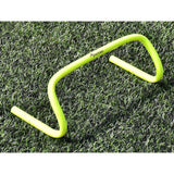 A Precision Training Agility Hurdle in yellow sits on green grass, perfect for lateral speed drills or stride exercises to enhance agility.