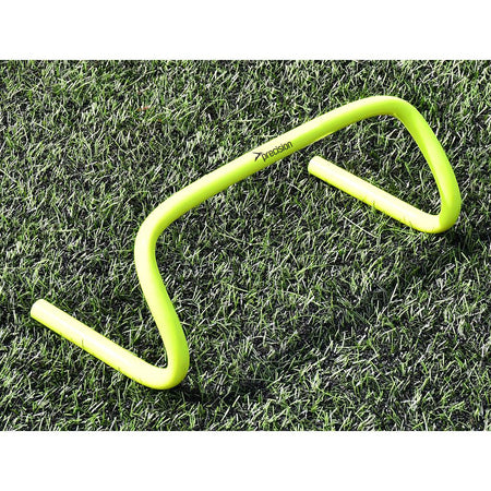 A Precision Training Agility Hurdle in yellow sits on green grass, perfect for lateral speed drills or stride exercises to enhance agility.