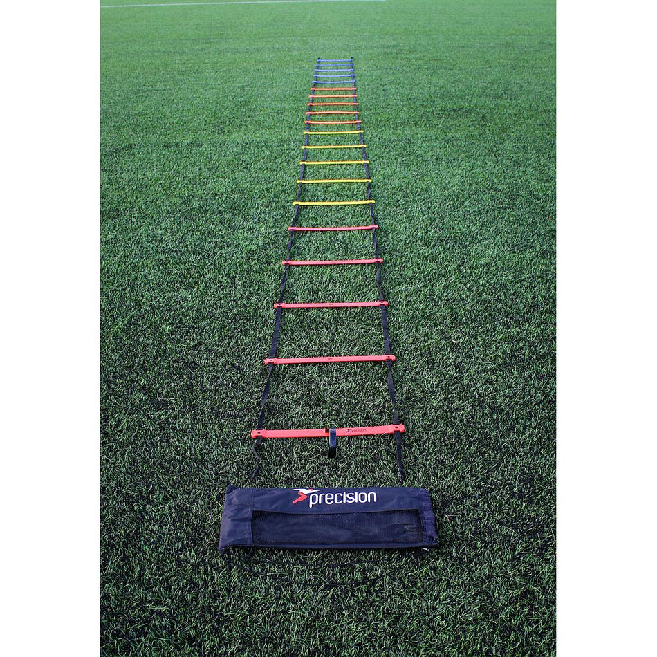 The Precision Training Speed Ladder with multicolored rungs is laid on green grass for footwork drills, and a black Precision Training bag sits at the end nearest the camera.