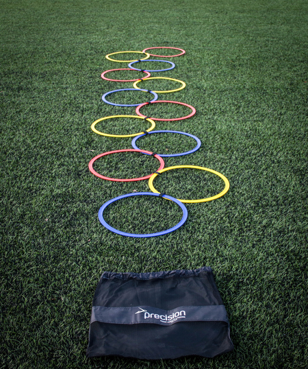The Precision Training Speed Agility Hoop Ladder features colorful hoops arranged in a zigzag on artificial grass, perfect for coordination drills. Includes a black mesh bag labeled Precision at the front.