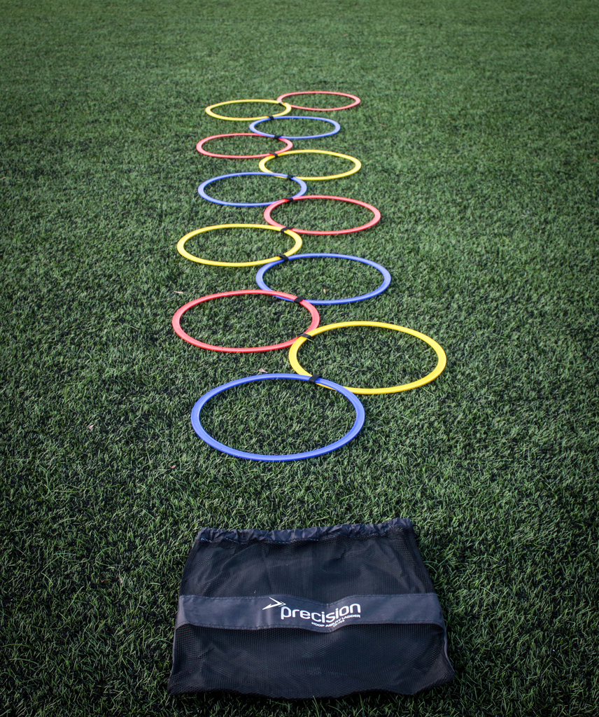 The Precision Training Speed Agility Hoop Ladder features colorful hoops arranged in a zigzag on artificial grass, perfect for coordination drills. Includes a black mesh bag labeled Precision at the front.