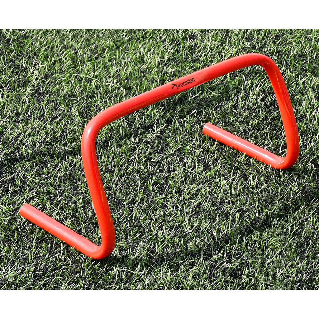 The Precision Training Precision Agility Hurdle, in bright orange, stands on green artificial grass—ideal for agility drills, lateral speed work, and striding exercises in sports training.