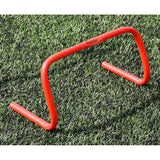 The Precision Training Precision Agility Hurdle, in bright orange, stands on green artificial grass—ideal for agility drills, lateral speed work, and striding exercises in sports training.